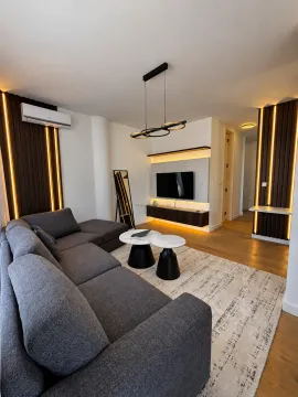 Modern living room with a sectional sofa, TV, and decorative lighting. - image 3