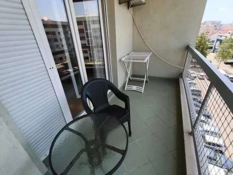 Covered balcony with a table, chair, and clothes drying rack. - image 4