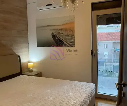 Spavaća soba sa krevetom, noćnim stočićem i balkonskim vratima. - image 7