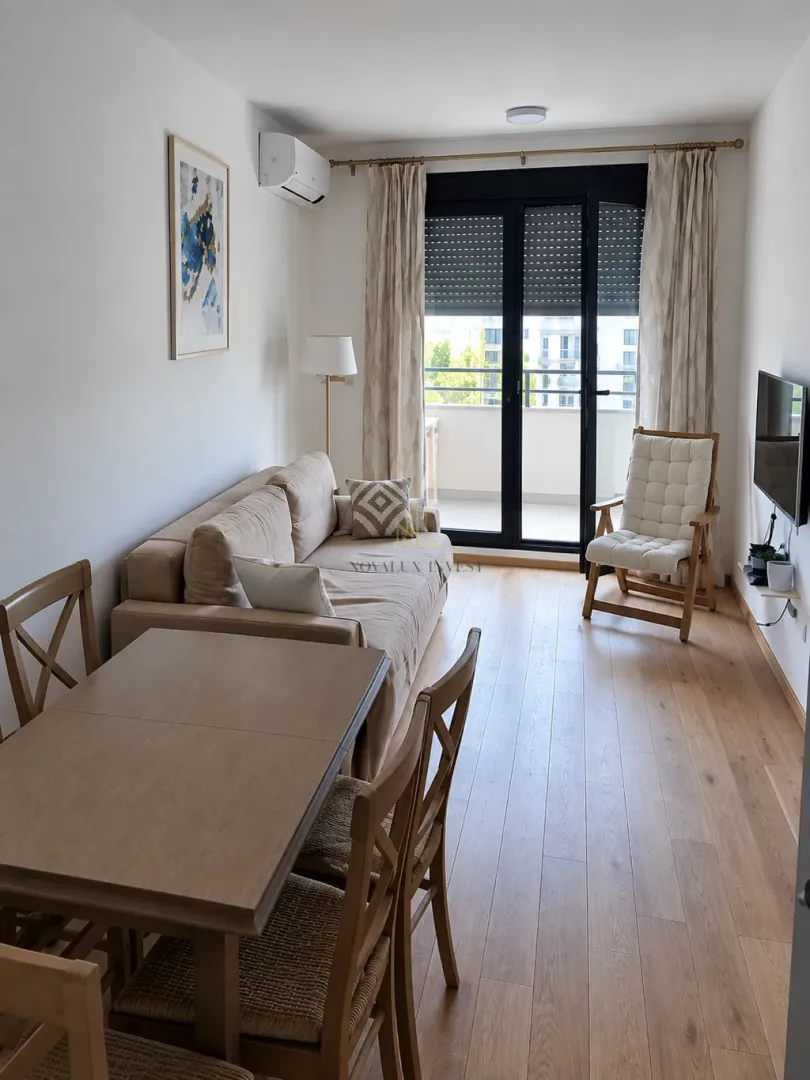Living room with a sofa, dining table, and access to the terrace.