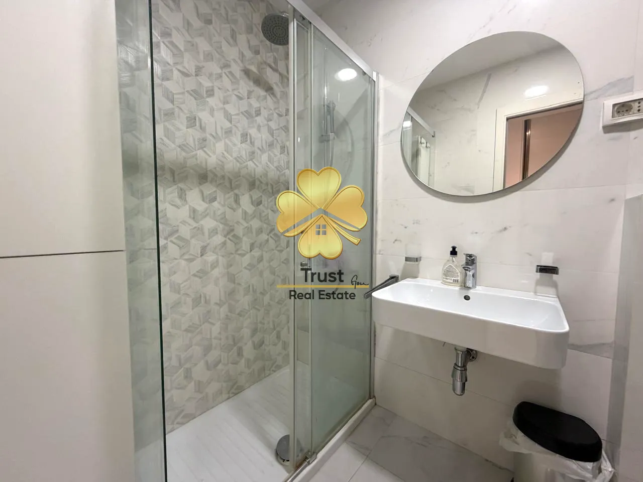 Modernly equipped bathroom with a shower cabin and washbasin.