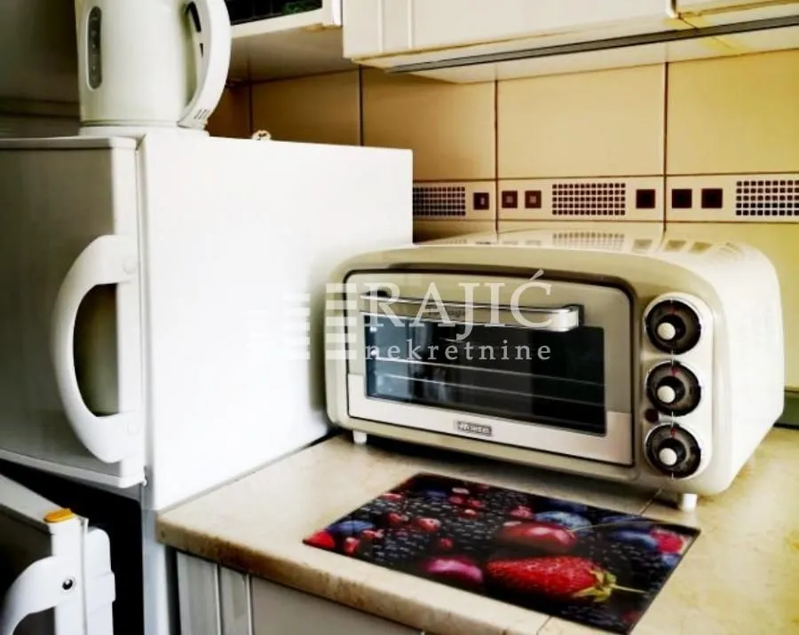 Part of the kitchen with a refrigerator, small oven, and kitchen units.
