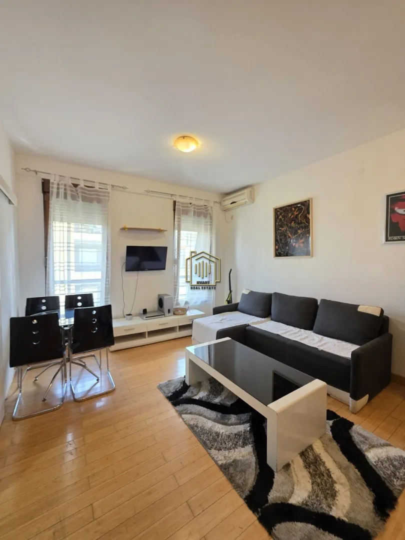 Living room with sofa, TV and dining table.