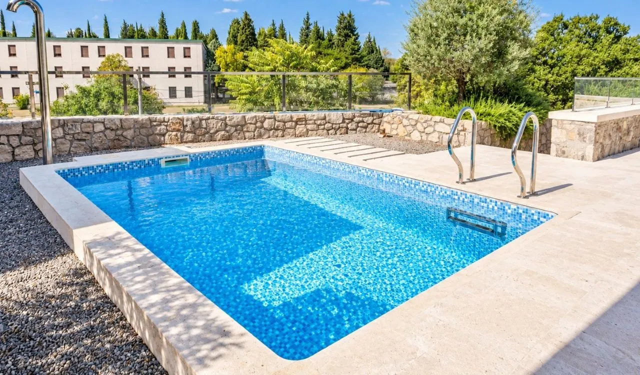 Swimming pool with a paved patio and landscaped yard.