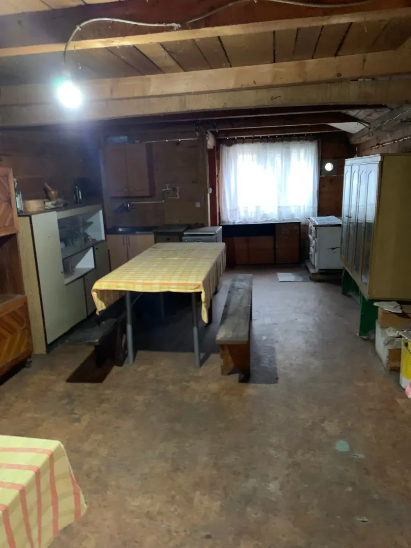 Starija rustična kuhinja sa drvenim elementima i trpezarijskim stolom.