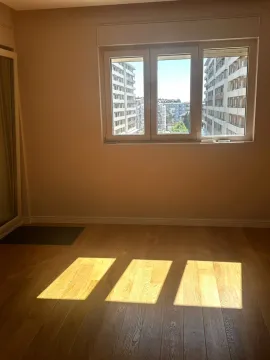 Empty room with hardwood floors and a window overlooking city buildings. - image 7