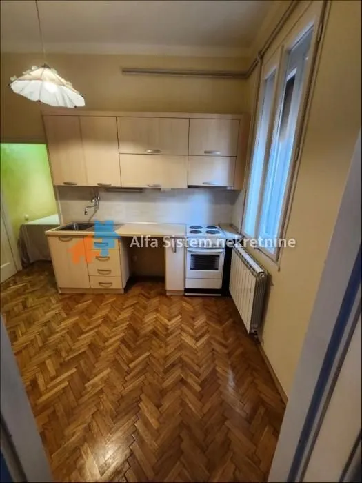 Kitchen with wooden cabinets, stove, and parquet flooring.