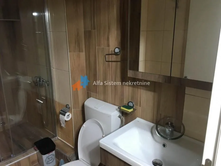 Compact bathroom with a shower cabin, sink, and toilet.