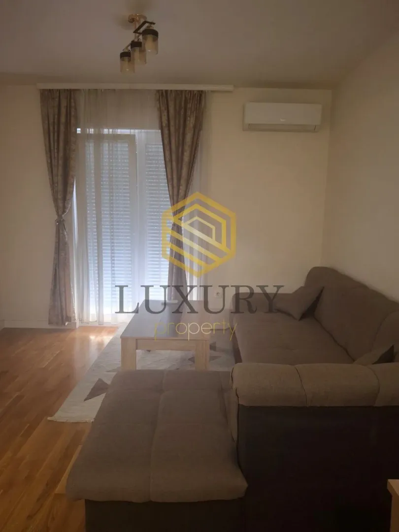 Living room with a sectional sofa, coffee table, and balcony doors.