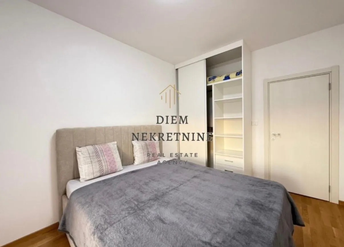 Namještena spavaća soba sa bračnim krevetom i ugradnim plakarom.