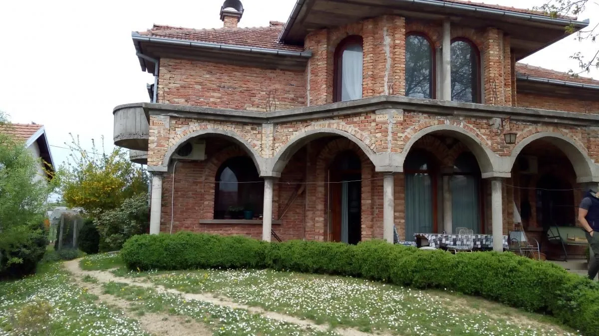 Spoljašnjost kuće od cigle sa tremom i lukovima u dvorištu.