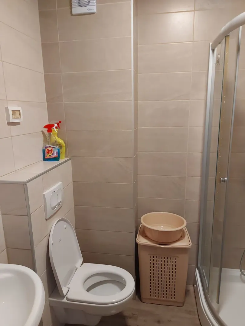 Jednostavno kupatilo sa tuš kabinom i svijetlim pločicama.