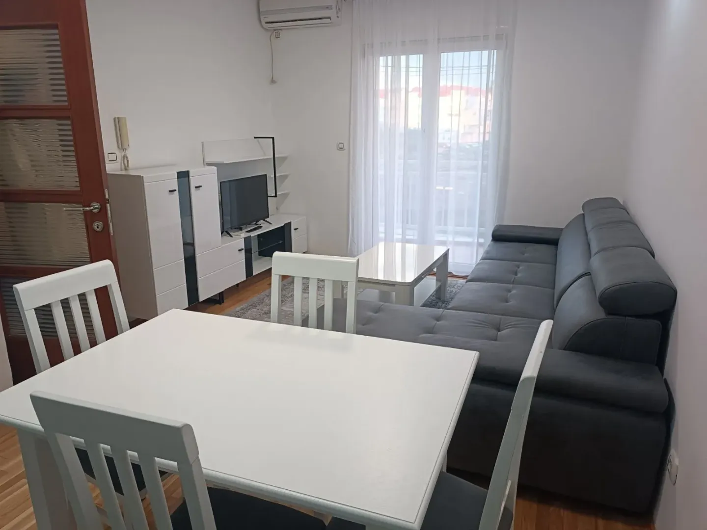 Living room with sofa, dining table, and TV unit.