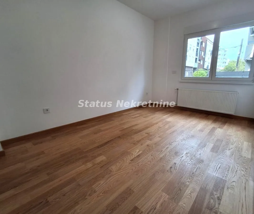 Empty room with wooden flooring and a window.