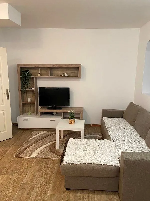Dnevna soba sa garniturom, televizorom i drvenom komodom.