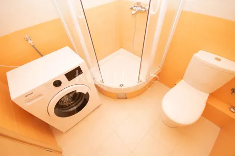 Bathroom equipped with a shower cabin, toilet, and washing machine. - image 8