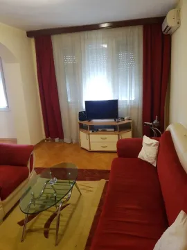 Living room with a red sofa, a glass coffee table, and a TV. - image 2
