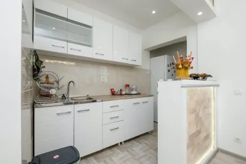 Modern kitchen with white cabinetry and a wood-grain countertop. - image 4