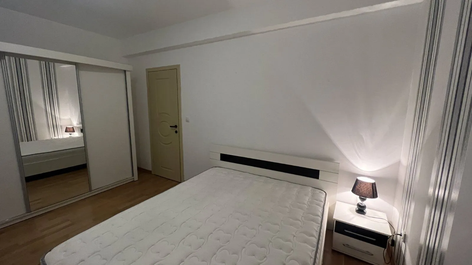 Simply furnished bedroom with a double bed and a mirrored wardrobe.