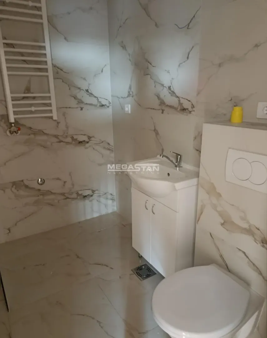Kupatilo obloženo mermernim pločicama sa umivaonikom i WC šoljom.