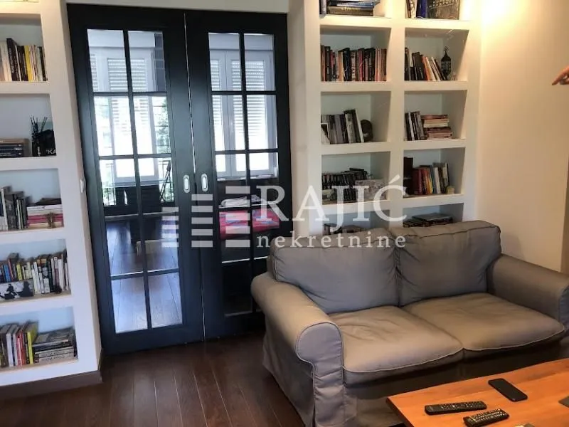 Living room with sofa, built-in bookshelves, and glass doors.