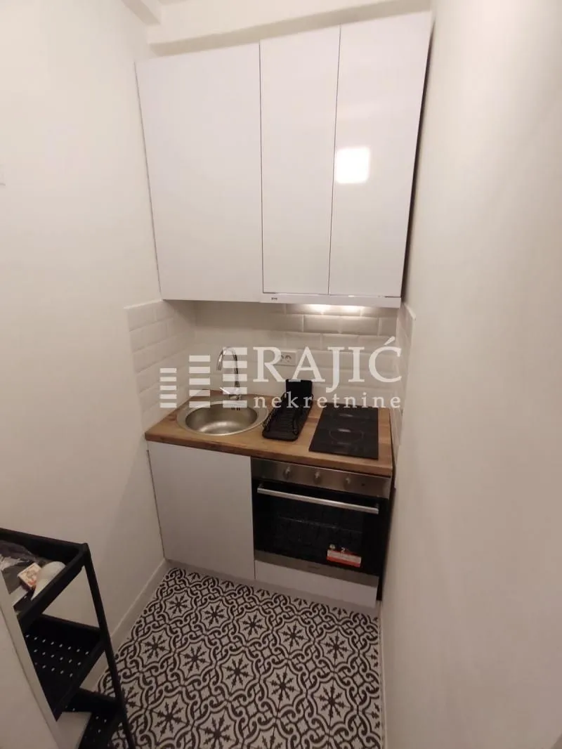 Small kitchen with white cabinets and built-in appliances.