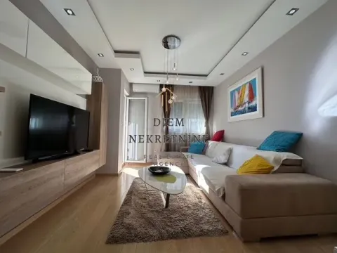 Living room with a sofa, TV, and drop ceiling with lighting. - image 2