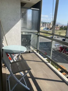 A bright balcony with a small table, chairs, and a view of the surroundings. - image 10