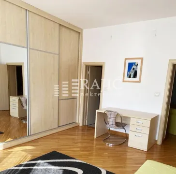 Furnished bedroom with a large built-in wardrobe and a desk. - image 6