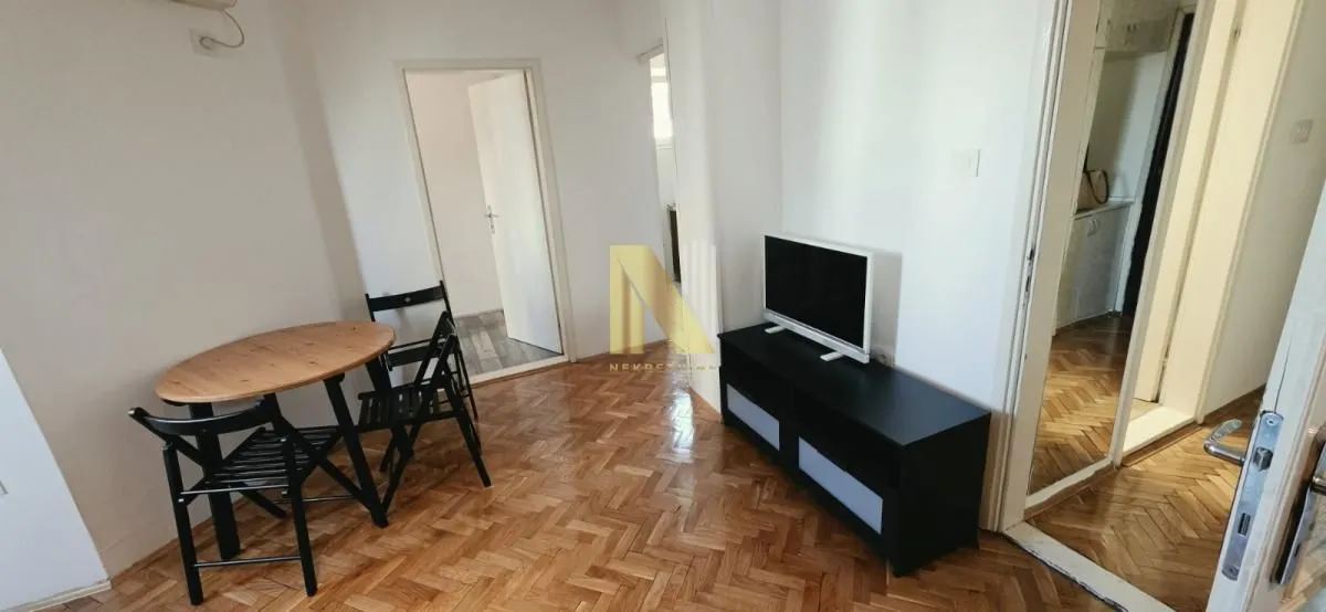 Manja dnevna soba sa trpezarijskim stolom i televizorom.