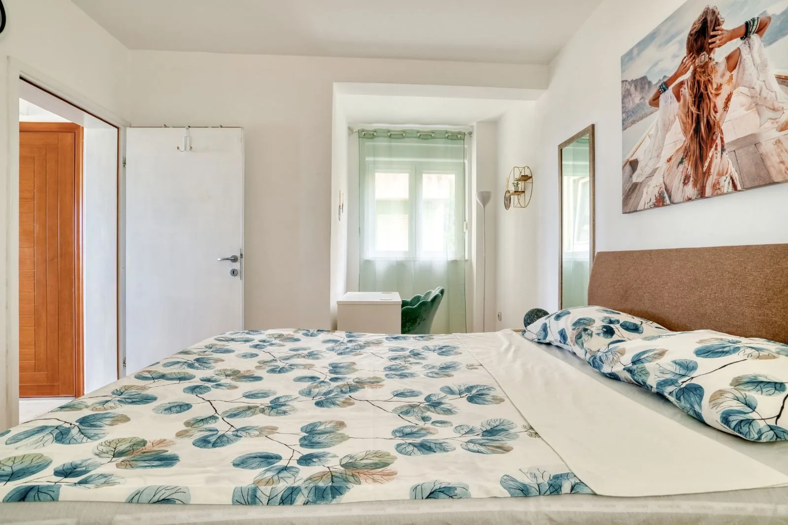 Furnished bedroom with a double bed, window, and wall art.