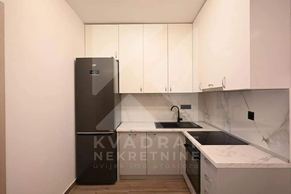 Small equipped kitchen with white cabinets and a black refrigerator.