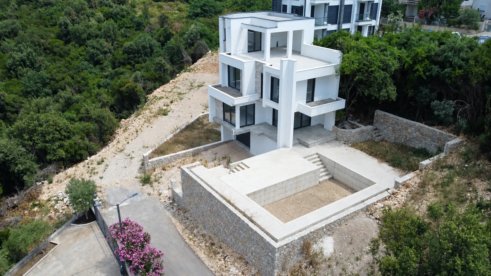 Pogled iz vazduha na modernu višespratnu kuću sa dvorištem u izgradnji.