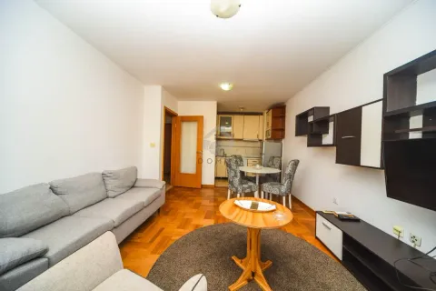 Living room with a sofa, TV, and dining area in the background. - image 3