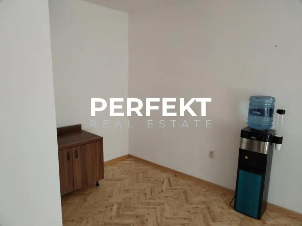 Empty room with parquet flooring and a water dispenser.