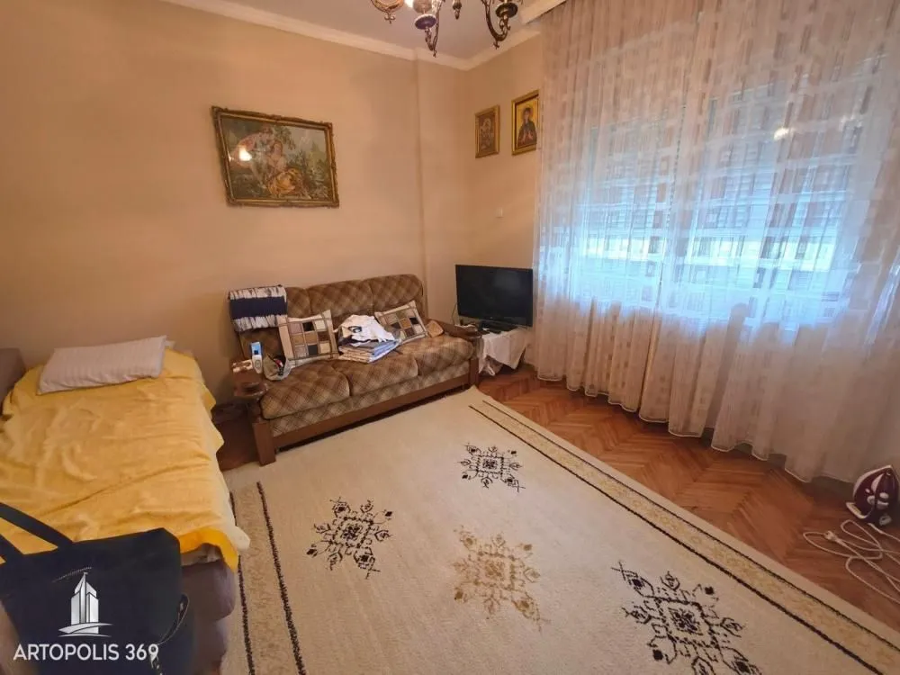Dnevna soba sa garniturom za sedenje, tepihom i velikim prozorom.