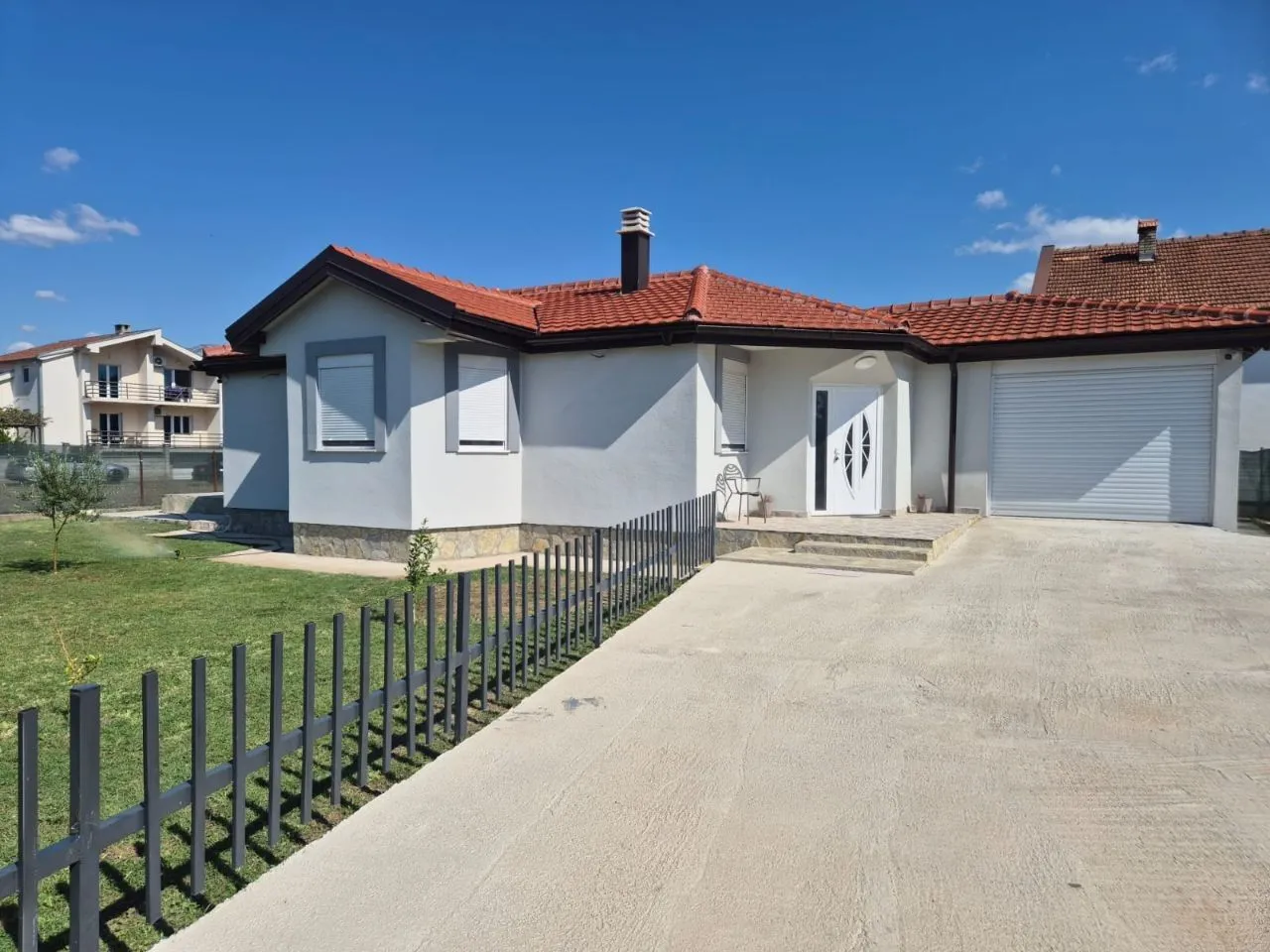 View of the front exterior of the house with a yard, entrance, and garage.