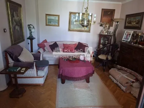 Dnevna soba sa garniturom, foteljom i umetničkim slikama na zidu. - image 2
