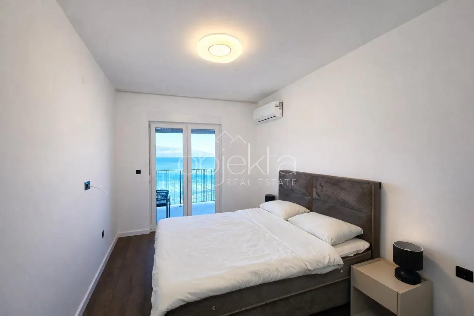 Bedroom with a double bed and access to a terrace with a sea view.