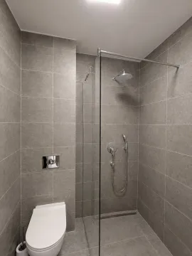 Moderno kupatilo sa tuš kabinom obloženom sivim pločicama. - image 14
