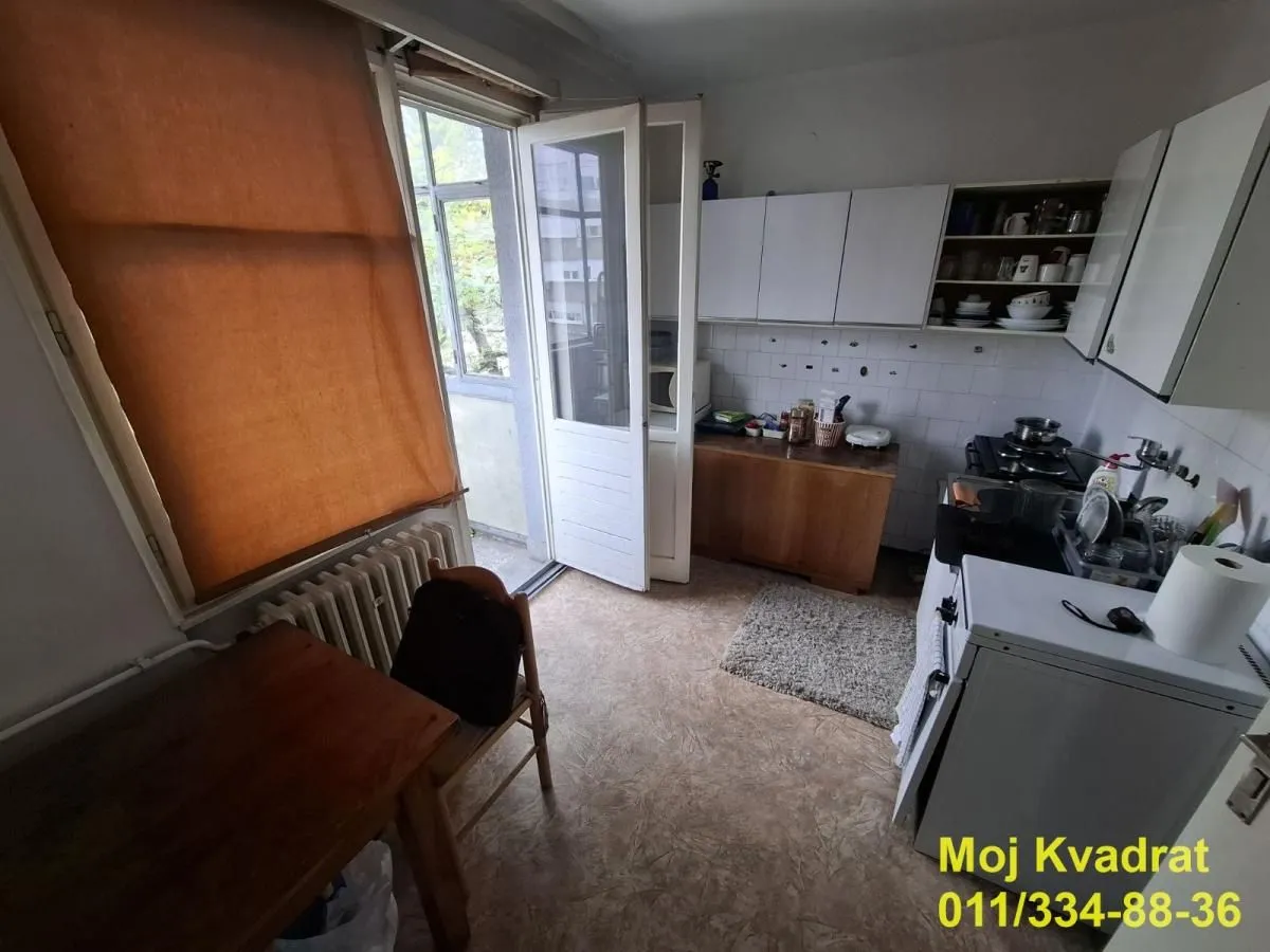 Small kitchen with white cabinets and access to the balcony.