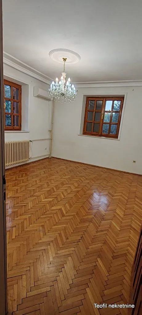 Empty room with wooden parquet flooring and a chandelier on the ceiling.
