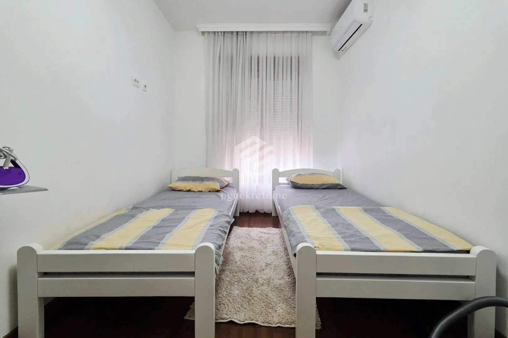 Bedroom with two single beds and white walls.