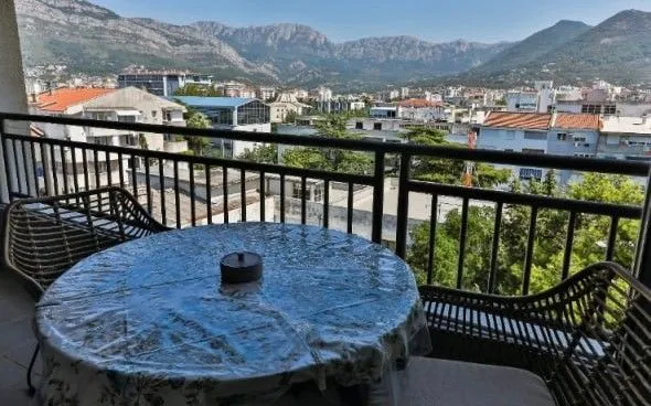 Namješten balkon sa stolom, stolicama i pogledom na grad i planine.