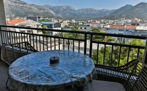 Namješten balkon sa stolom, stolicama i pogledom na grad i planine. - image 2
