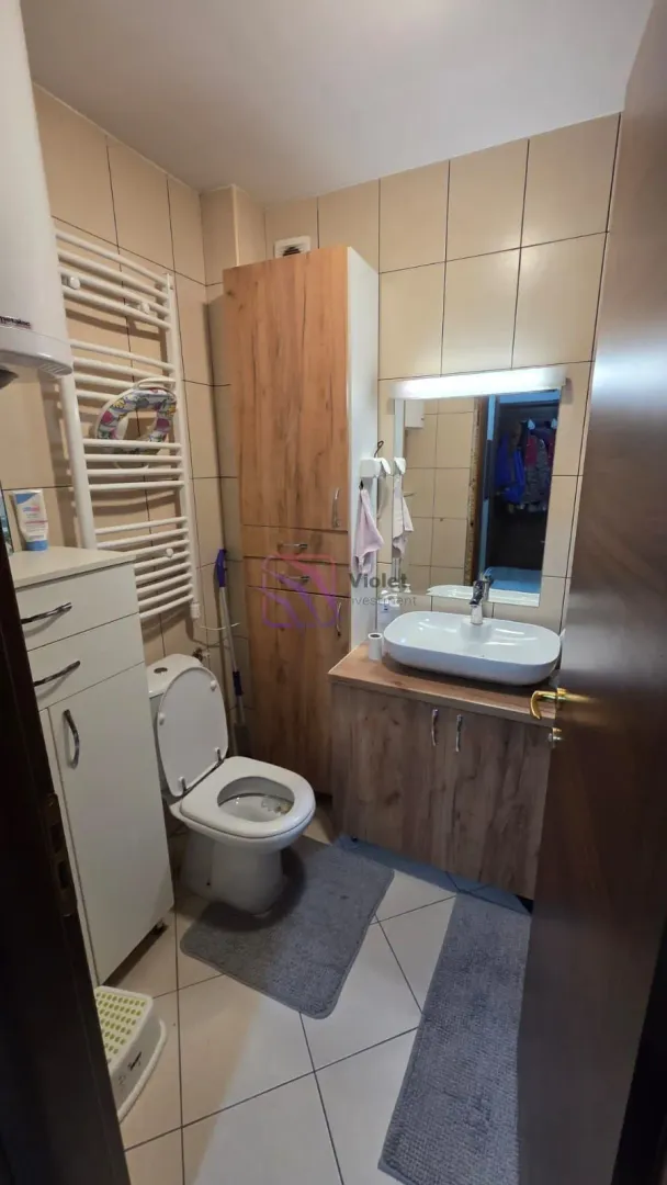 Manje kupatilo sa umivaonikom, WC šoljom, ormarićem i radijatorom za peškire.