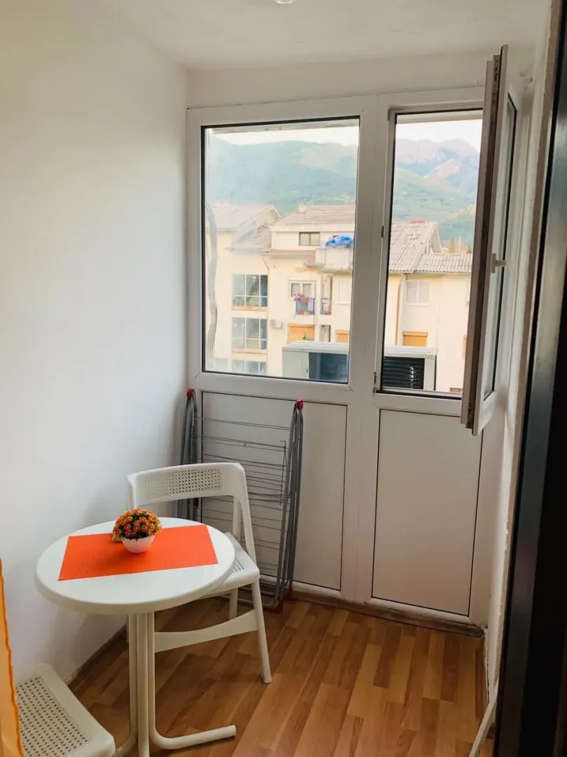 Manji zastakljeni balkon sa stolom, stolicama i pogledom na okolinu.