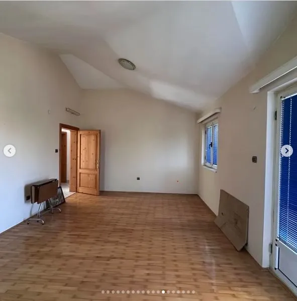 Prazna prostrana soba sa drvenim podom i svijetlim zidovima.