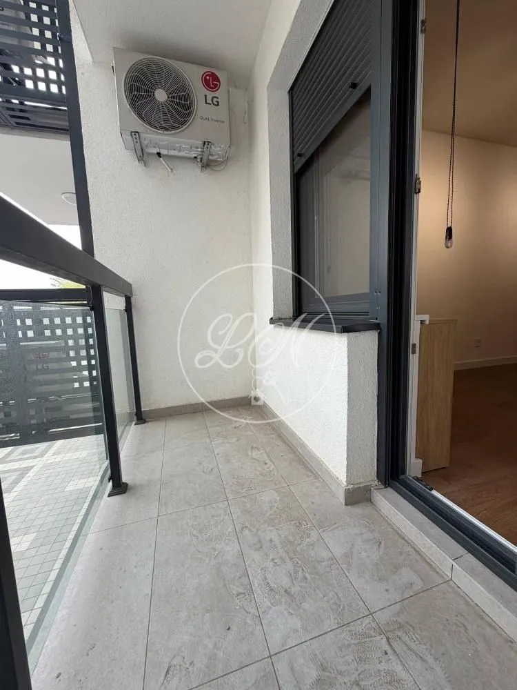Smaller tiled balcony with an external air conditioning unit and a glass railing.