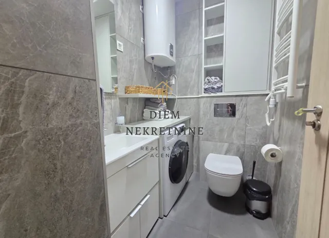 Modern bathroom with a walk-in shower, washbasin, and washing machine.